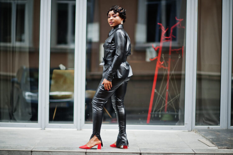 Fashionable beautiful african american woman posing in black leather jacket and pants at street