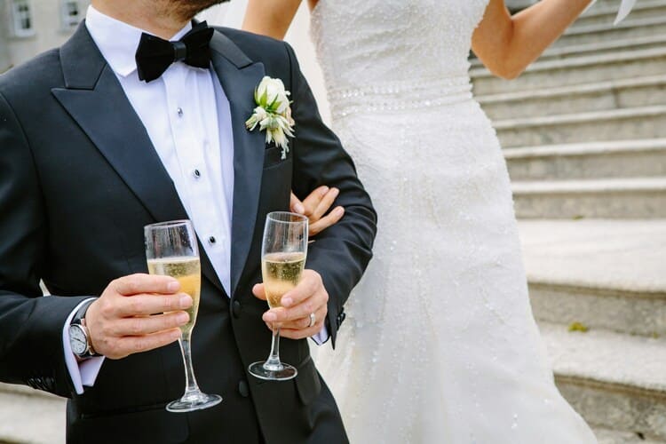 Man Wearing Tuxedo with bride in background
