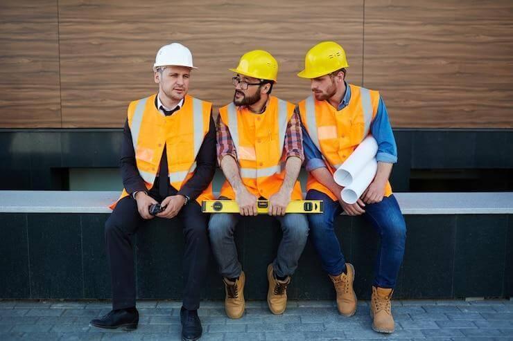 Construction workers wearing long sleeve shirts sitting on a bench