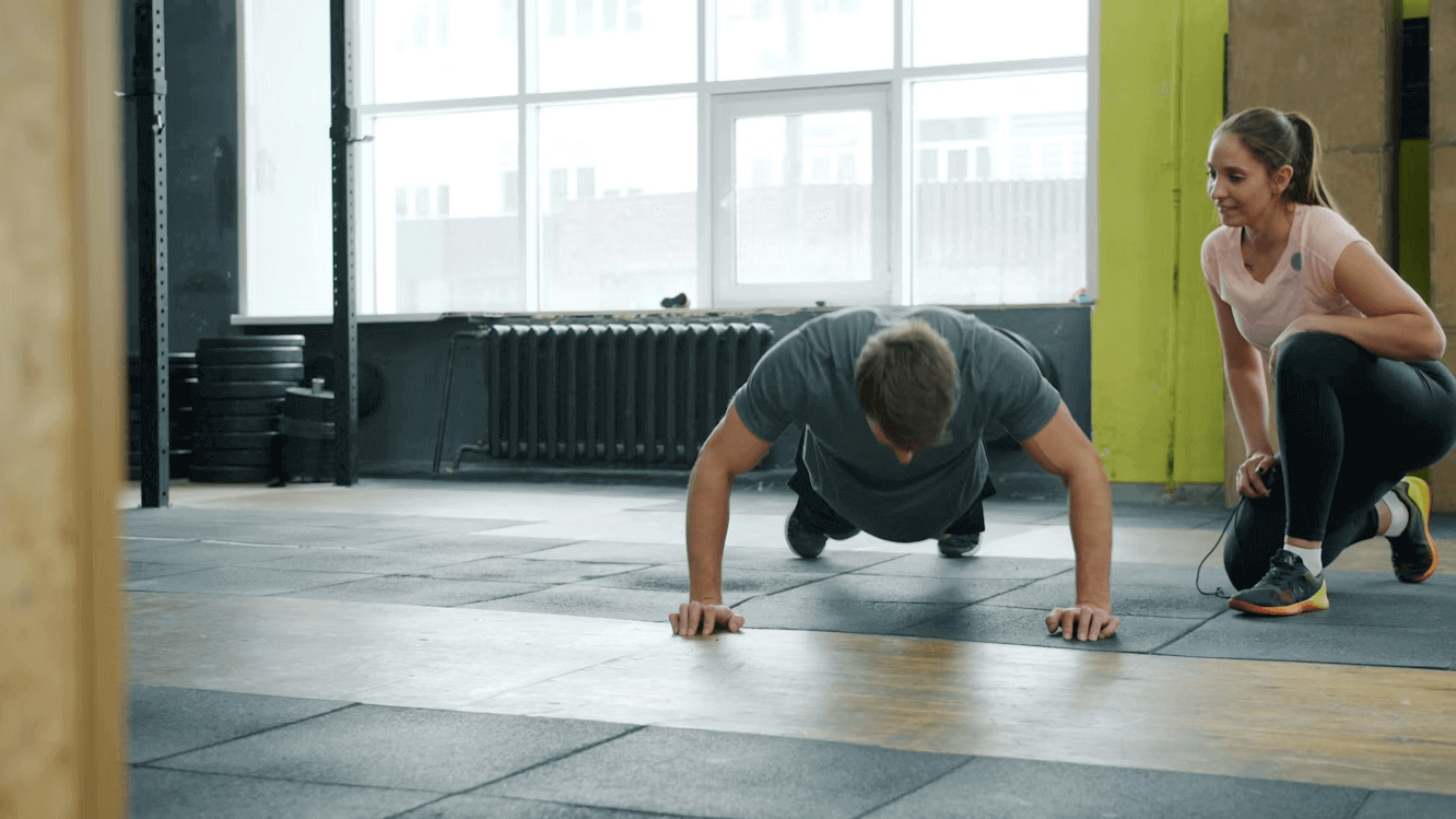 Man and woman doing push ups in gym fitness routine