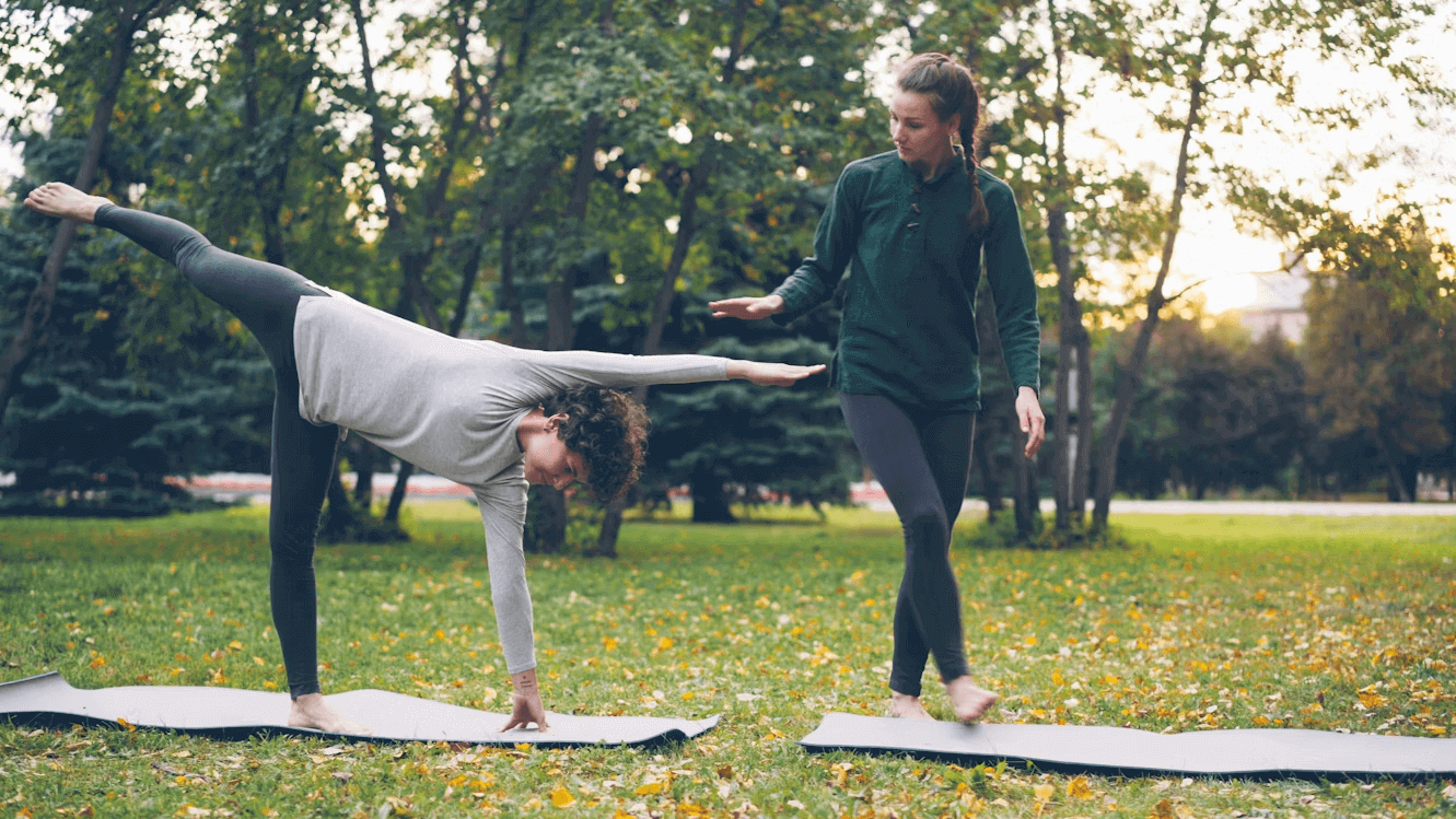 Man and woman practicing yoga in a park