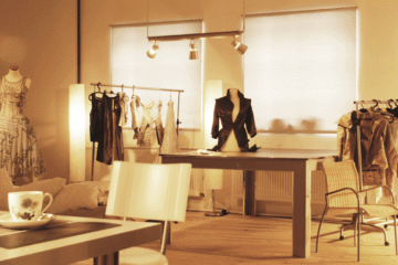 Messy fashion studio with racks of clothes and a central table