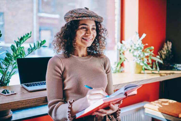 female author looking away thinking about article holding textbook in hands