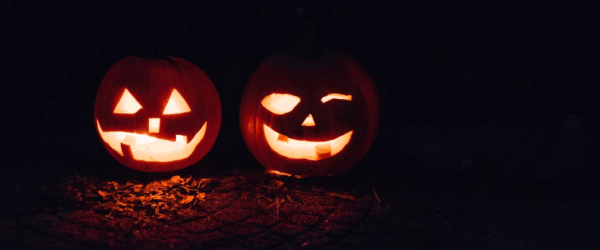 Two carved pumpkins illuminated in the dark