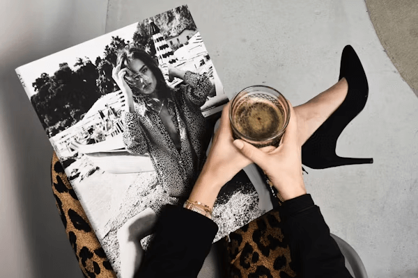 Woman holding a glass of wine beside a book during Fashion Week